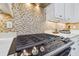 Close up of stove in the kitchen with white cabinets, stainless steel appliances and a tiled backsplash at 834 Birdie Way, Apollo Beach, FL 33572