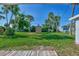 Spacious backyard featuring a storage shed surrounded by lush green grass and tropical palm trees at 8469 Aero Ave, North Port, FL 34287