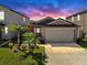 Beautiful home exterior with a two-car garage, green lawn, and tropical palm trees at sunset at 10205 Cool Waterlily Ave, Riverview, FL 33578