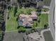 Aerial shot of estate with a tile roof, screened pool, landscaped grounds, and circular driveway at 13551 Carnoustie Cir, Dade City, FL 33525