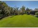 An expansive backyard featuring mature trees and manicured lawn surrounds the home at 13551 Carnoustie Cir, Dade City, FL 33525
