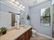 Bright bathroom featuring a vanity, toilet, window with blinds, and walk-in shower at 13551 Carnoustie Cir, Dade City, FL 33525