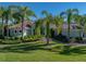 Beautiful exterior view featuring a well-manicured lawn and lush landscaping with palm trees at 13551 Carnoustie Cir, Dade City, FL 33525