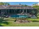 Beautiful screened-in pool area surrounded by lush landscaping and comfortable lounge chairs at 13551 Carnoustie Cir, Dade City, FL 33525
