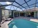 A pristine screened-in pool offers steps, a lounge chair, and access to the home's interior at 13551 Carnoustie Cir, Dade City, FL 33525