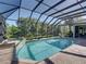 A screened-in pool area offers a hot tub, a waterfall, and views of the backyard at 13551 Carnoustie Cir, Dade City, FL 33525