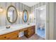 Bathroom with wood cabinets, oval mirrors, white countertops, blue wallpaper, and blue tile floor in a separate room at 13982 Whisperwood Dr, Clearwater, FL 33762