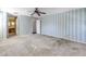 Unfurnished bedroom with blue wallpaper, white trim, ceiling fan, and access to a bathroom at 13982 Whisperwood Dr, Clearwater, FL 33762