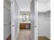 Hallway view of the bathroom, mirrored wall decor, carpet flooring, and white walls at 13982 Whisperwood Dr, Clearwater, FL 33762