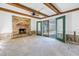 A living room boasts a brick fireplace, exposed beam ceiling and access to the patio at 13982 Whisperwood Dr, Clearwater, FL 33762
