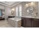 Modern bathroom featuring dual vanities, a soaking tub with decorative tile surround, and a large round mirror at 14123 Barrington Stowers Dr, Lithia, FL 33547