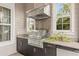 A stainless steel grill under a vent hood, surrounded by granite countertops and dark cabinets, creates an outdoor kitchen at 14123 Barrington Stowers Dr, Lithia, FL 33547
