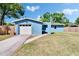 Quaint one-story home with a white garage door, blue exterior, and an arched entryway at 2035 Ronald Cir, Seffner, FL 33584