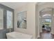 Luxurious bathroom featuring modern soaking tub with natural light entering through designer patterned windows at 218 Pesaro Dr, North Venice, FL 34275