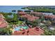 Stunning aerial view of a resort featuring a sparkling pool, lush landscaping, and waterfront condos with terracotta roofs at 2730 Via Tivoli # 321B, Clearwater, FL 33764