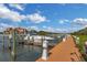 Picturesque marina view with a sleek white boat docked alongside a wooden pier under a bright blue sky with scattered clouds at 2730 Via Tivoli # 321B, Clearwater, FL 33764