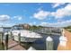Picturesque marina view with a sleek white boat docked alongside a wooden pier under a bright blue sky with scattered clouds at 2730 Via Tivoli # 321B, Clearwater, FL 33764