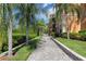 Beautiful community walkway lined with lush landscaping and palm trees leading toward residential buildings with balconies at 2730 Via Tivoli # 321B, Clearwater, FL 33764