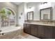 Bright bathroom features a soaking tub, double sinks with granite countertops, and a large window at 2905 Hillside Ramble Dr, Brandon, FL 33511