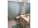 Bathroom featuring a sink, a toilet, a shower with a curtain, and neutral-colored tiles at 3120 Dole St, Holiday, FL 34691