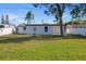 Backyard view shows the exterior of the house, green grass, and a white fence at 3249 Masonville Loop, Holiday, FL 34691