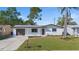 Charming one-story home with a gray roof, neutral paint and pretty landscaping in the front at 3249 Masonville Loop, Holiday, FL 34691
