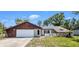 Charming single-story home featuring an attached garage, stone accents, and a cozy front yard with a white picket fence at 3276 Morven Dr, Spring Hill, FL 34609