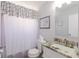 Functional bathroom with a patterned shower curtain, toilet, sink with granite countertop, and decorative mirror at 401 Dorchester Pl # 55, Sun City Center, FL 33573