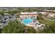 Aerial view of community pool, shuffleboard, and clubhouse set among lush landscaping and a pond at 401 Dorchester Pl # 55, Sun City Center, FL 33573
