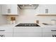 Close-up of kitchen cooktop, backsplash, and modern white cabinetry with sleek black hardware at 4405 W Euclid Ave, Tampa, FL 33629