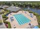 Aerial view of a large community pool with umbrellas and lounge chairs next to a lake at 5014 Sterling Manor Dr, Tampa, FL 33647