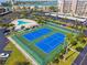 Aerial view of two tennis courts and a community pool surrounded by parking and tropical landscaping at 7300 Sun Island S Dr # 1705, South Pasadena, FL 33707