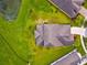 Aerial view of the home with a gray roof, lush landscaping, and a pond nearby at 8100 Olive Brook Dr, Wesley Chapel, FL 33545