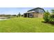 Large backyard with green grass, landscaping, and a view of the pond at 8100 Olive Brook Dr, Wesley Chapel, FL 33545