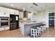Kitchen with granite counters, stainless appliances, white cabinets, island with seating, pendant lighting and wood floors at 8100 Olive Brook Dr, Wesley Chapel, FL 33545