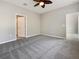 An empty gray bedroom with a ceiling fan and gray carpet, with two doorways showing at 8314 Deerland Bluff Ln, Riverview, FL 33578