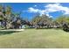 Inviting community park with lush green space, mature trees, and a walking path overlooking a lake at 9748 Ibis Grove Blvd, Wesley Chapel, FL 33545