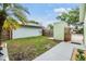 Fenced backyard with a lush green lawn and walkway leading to a private outdoor space at 10306 Green Grove Pl, Tampa, FL 33624