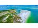 Expansive aerial view of a white sand beach with clear turquoise water and a distant view of the city at 1754 Patricia Ave, Dunedin, FL 34698