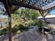 Outdoor deck with a pergola overlooking the landscaped backyard garden and lake at 1754 Patricia Ave, Dunedin, FL 34698