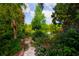 Lush backyard featuring a stone path, pond, and vibrant flowers creating a serene and inviting outdoor retreat at 1754 Patricia Ave, Dunedin, FL 34698