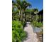 Stone path leading to garden and a pergola in the backyard, surrounded by greenery and flower beds at 1754 Patricia Ave, Dunedin, FL 34698