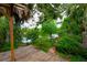 Backyard view from wooden deck, featuring lush greenery, tropical trees, and a serene lake at 1754 Patricia Ave, Dunedin, FL 34698