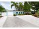 Single-story home with a bright blue exterior, white gravel yard, and lush tropical foliage at 1754 Patricia Ave, Dunedin, FL 34698