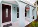 Inviting covered porch with archways, decorative front door, and colorful hanging flower pot at 1754 Patricia Ave, Dunedin, FL 34698