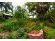 Lush garden with colorful flowers, a brick-lined planter, and a charming pergola in the background at 1754 Patricia Ave, Dunedin, FL 34698
