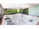 Large, inviting hot tub in a screened-in enclosure, offering views of the lush backyard at 1754 Patricia Ave, Dunedin, FL 34698