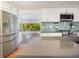 Modern kitchen with stainless steel appliances, white cabinets, gray countertops and a tile backsplash at 1754 Patricia Ave, Dunedin, FL 34698