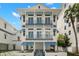 Elegant three-story home featuring balconies, blue awnings, and modern architectural design at 19 Somerset St, Clearwater Beach, FL 33767