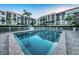 Community pool surrounded by a white fence, palm trees, and condo buildings at 19111 Vista Bay Dr # 402, Indian Shores, FL 33785